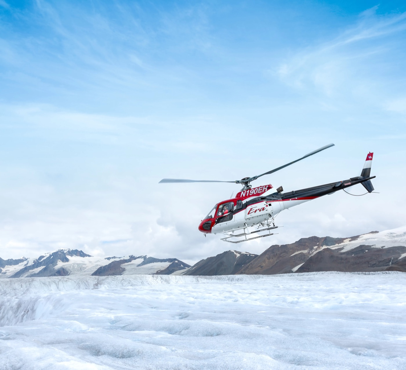 Helicopter landing on an Alaska icefield with mountains behind