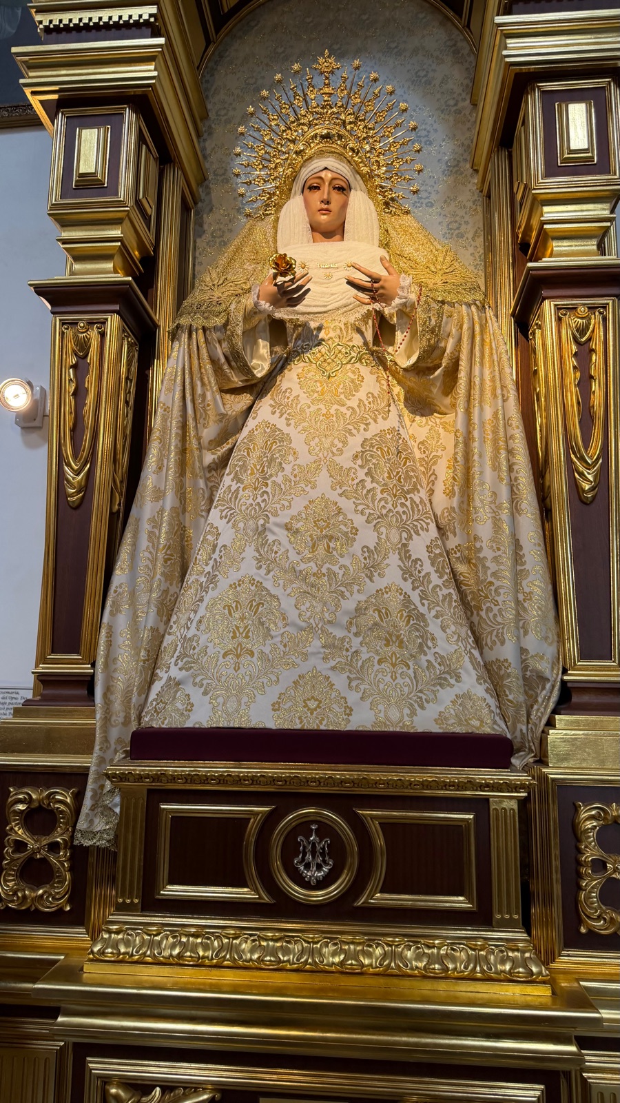 An ornate gilded altarpiece with a crowned figure inside the church in Marbella old town