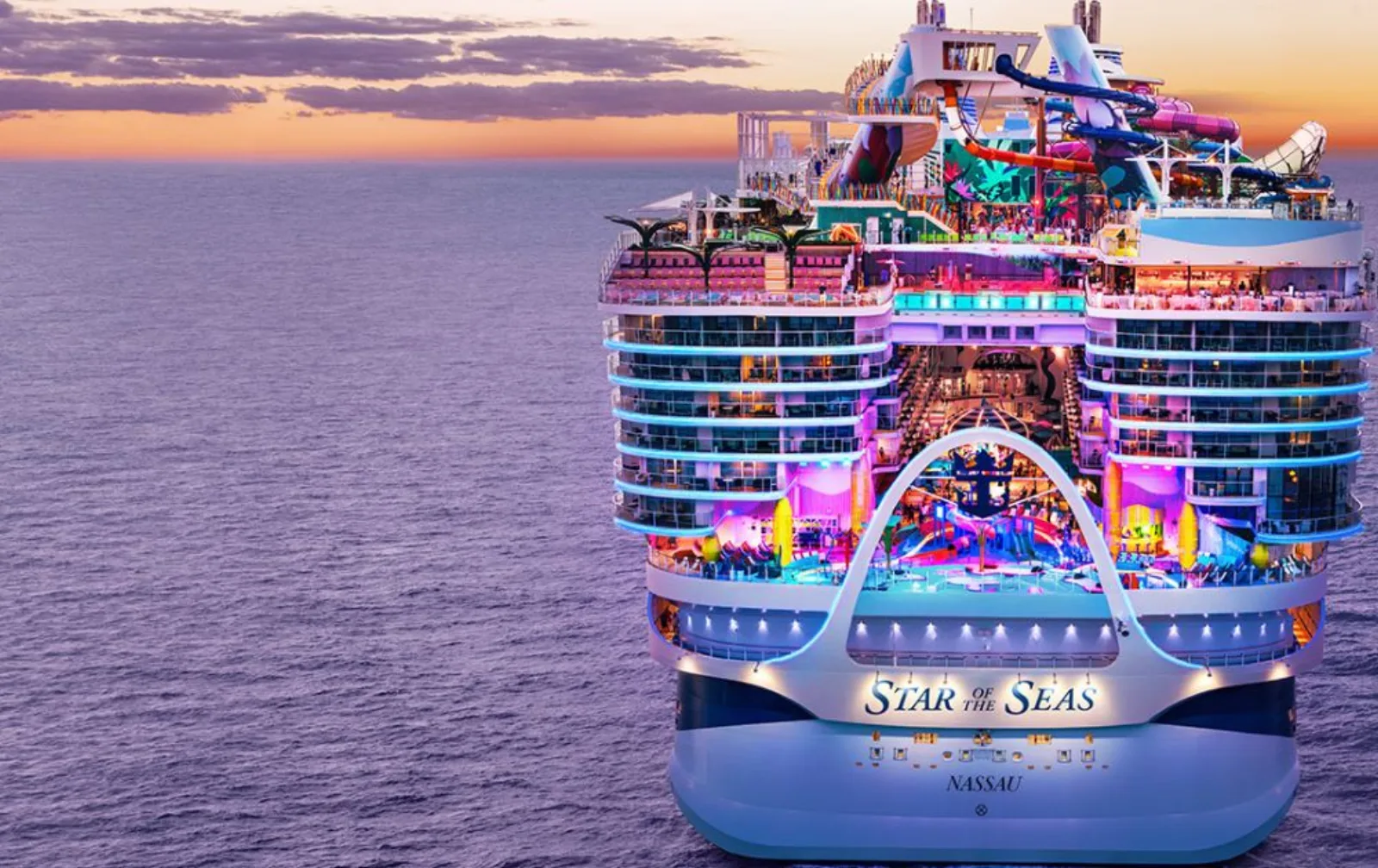 The aft of a large modern cruise ship lit up at sunset over open water