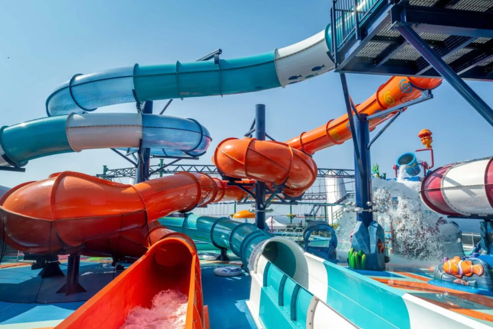 A cruise ship top-deck water park with bright spiraling slides under a clear sky