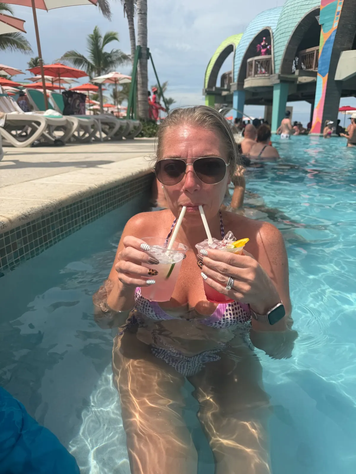 Miguel's wife Ashley in the Royal Beach Club pool holding a drink in each hand
