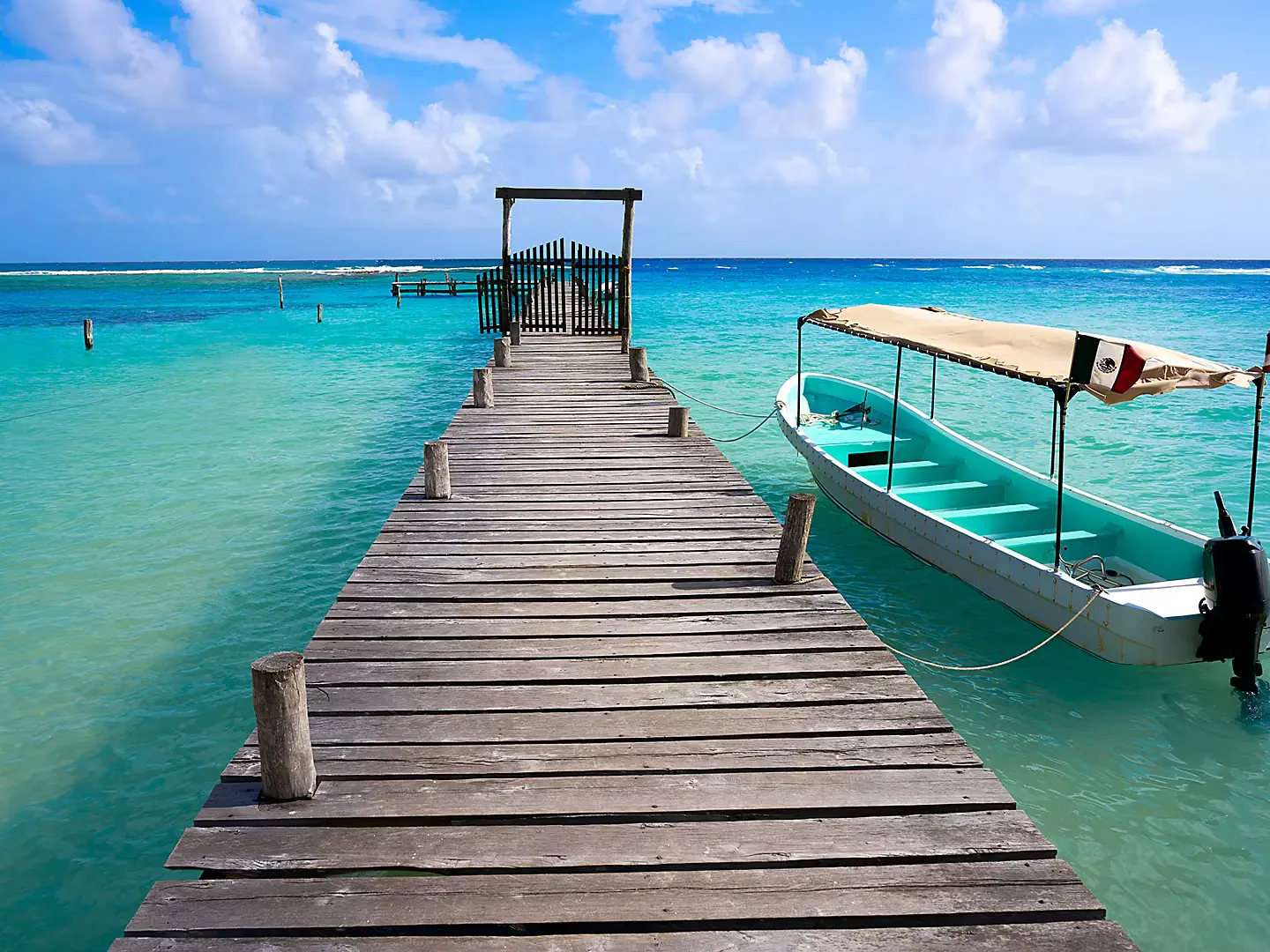 Wooden dock over turquoise Caribbean water with a boat